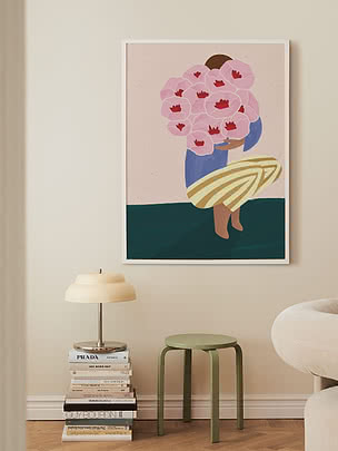 Poster Woman With Pink Flowers in cornice bianca su parete crema sopra una pila di libri con lampada a cupola e uno sgabello verde