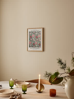 Indrammet William Morris-plakat med blomstermønster over et dækket spisebord
