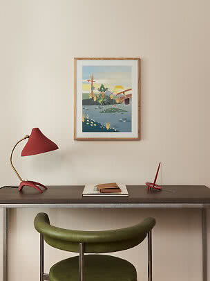 Inramad poster med illustrerad fiskescen över skrivbord med röd lampa och grön stol