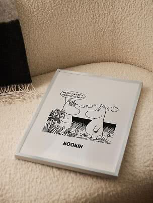 Poster Moomin incorniciato con illustrazione in bianco e nero su morbida poltrona beige