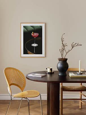 Poster incorniciato con cocktail rosa appeso sopra il tavolo da pranzo