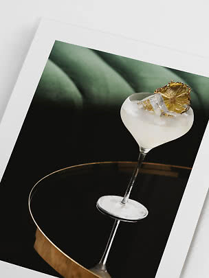 Framed print of a cocktail glass on a black table with ice cubes and a dried lemon slice