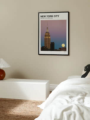 Inramad New York City-poster med Empire State Building och fullmåne på beige sovrumsvägg