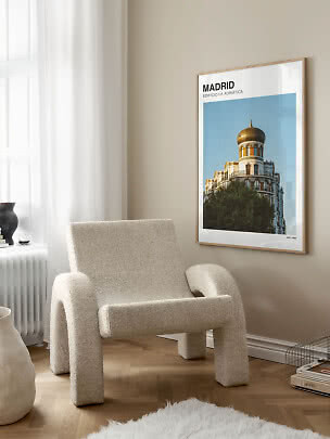 Indrammet Madrid-plakat med bygning og gylden kuppel på beige væg ved en cremefarvet lænestol