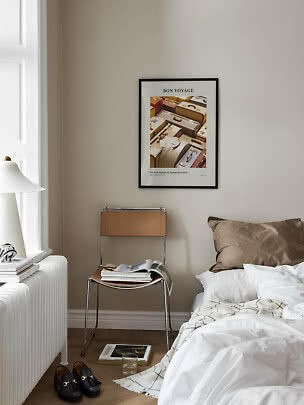 Gerahmtes Bon-Voyage-Poster mit Koffern über einem Stuhl im ruhigen Schlafzimmer