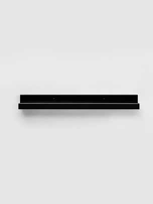 Schwarzes minimalistisches Wandregal an einer weißen Wand montiert