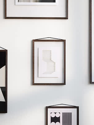Dunkler Holzrahmen mit abstraktem beigem Linienprint an weißer Wand