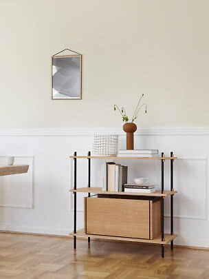 Lys træreol med sorte ben, vase med blomster og bøger i minimalistisk stue