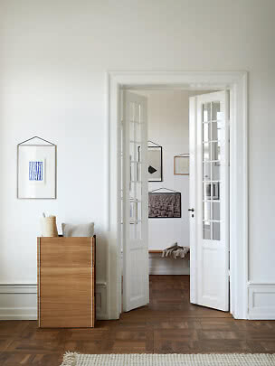 Wooden cabinet with cushion and roll by a white wall and open French doors