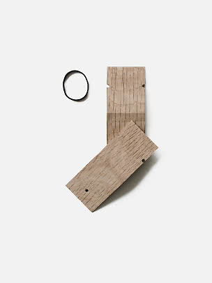 Moebe Pinch aus Eiche mit zwei Holzteilen und schwarzem Gummiband auf weißem Hintergrund