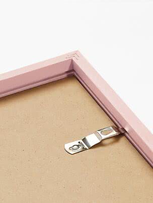 Primo piano del retro di una cornice rosa con gancio metallico