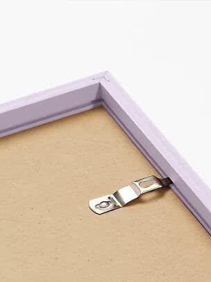 Primo piano del retro di una cornice lilla chiaro con gancio metallico