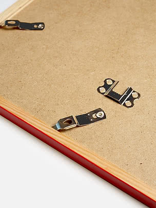 Retro di una cornice quadrata in rosso con il pannello posteriore in MDF e gli attacchi metallici per appenderla