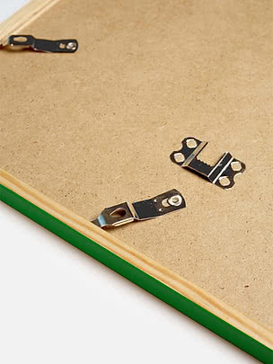 Retro di una cornice quadrata in verde con il pannello posteriore in MDF e gli attacchi metallici per appenderla