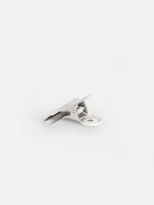Hvid metalclips med fjeder og rundt hul på hvid baggrund