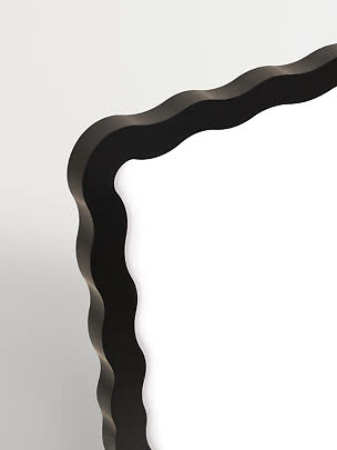 Gros plan d’un cadre de miroir noir aux bords ondulés sur fond clair