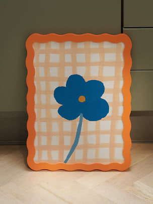 Dekorativt rektangulært panel med bølget orange kant, ternet mønster og blå blomst
