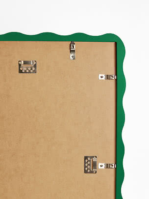 Back of a green frame with wavy edge and metal hanging clips