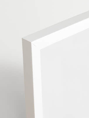 Nærbillede af hjørnet på et hvidt minimalistisk bord eller kabinet mod lys baggrund