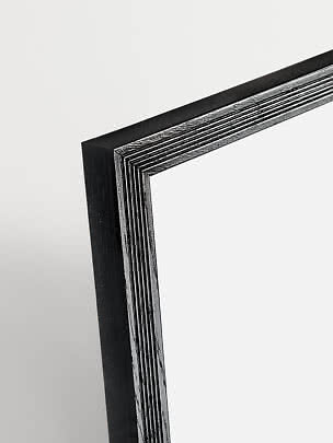 Primo piano dell’angolo di una cornice in legno nera con profilo scanalato lucido