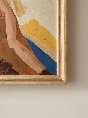 Gros plan d’une affiche d’art abstrait dans un cadre en bois clair, avec touches jaune, beige et bleu
