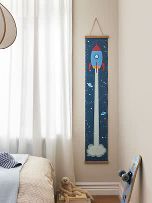 Rocket-themed height chart hanging on the wall in a child's bedroom