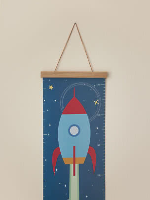 Kids height chart with colorful rocket on a blue starry background, hung with a wooden frame and cord.