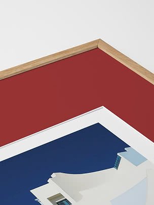 Primo piano in diagonale dello smusso di un passepartout in rosso dentro una cornice in rovere, con un poster blu sotto vetro