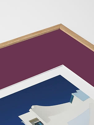 Primo piano in diagonale dello smusso di un passepartout in prugna dentro una cornice in rovere, con un poster blu sotto vetro