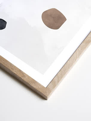 Abstract print in a light wood frame with beige and black organic shapes on a white background