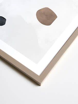 Abstract art print in a light wood frame with beige and black organic shapes on a white background