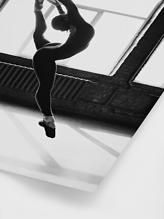 Photo en noir et blanc d’une danseuse en pose de ballet souple dans un studio lumineux