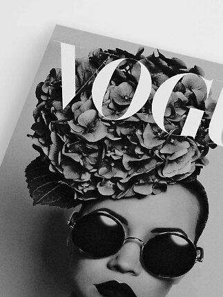 Black-and-white Vogue magazine cover with woman in round sunglasses and flowers on her head