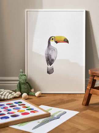 Gerahmtes Poster mit Tukan-Aquarell, an die Wand gelehnt auf dem Boden im Kinderzimmer