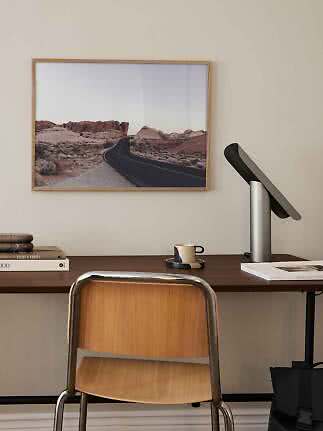 Bureau met stoel, lamp en ingelijste woestijnfoto met kronkelende weg aan de muur