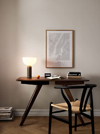 Dunkler Holzschreibtisch mit schwarzem Stuhl, leuchtender Tischlampe und gerahmtem New-York-Poster