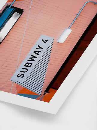 Schild „Subway 4“ an rosa Backsteinwand mit Lampen und sichtbaren Leitungen