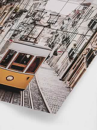 Yellow tram on a steep cobblestone street between narrow buildings and overhead wires