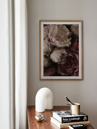 Indrammet blomsterplakat over et træbord med bøger, kop og hvid dekorationslampe