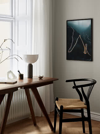 Indrammet vægkunst med snoet bjergvej over et skrivebord i et lyst, moderne rum