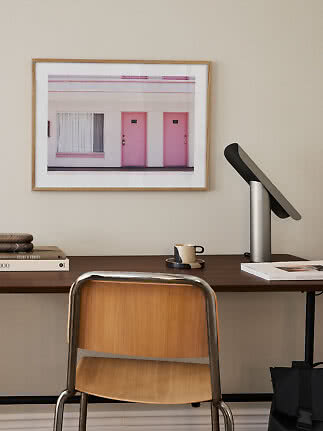 Escritorio con silla, lámpara y cuadro enmarcado con dos puertas rosas en la pared