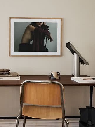 Scrivania in legno scuro con sedia, lampada da tavolo, tazza e quadro incorniciato