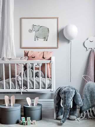 Kinderzimmer mit weißem Gitterbett, Elefantenbild, Kuscheltieren und Boxen mit Hasenohren.