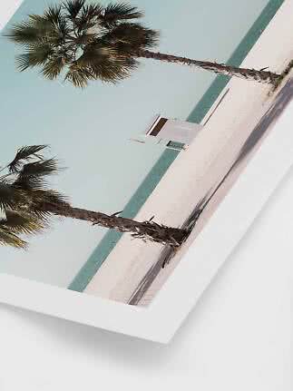 Ukośne zdjęcie palm na piaszczystej plaży, z turkusowym morzem i małą białą budką