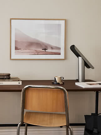 Bureau avec chaise en bois, lampe et affiche de plage encadrée au mur