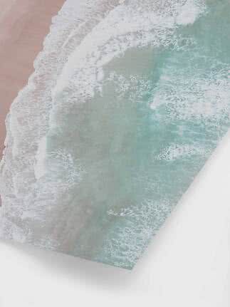 Aerial view of waves washing onto a pale pink sandy beach