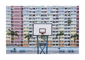 Basketball hoop in front of a colorful apartment block with palm trees and benches