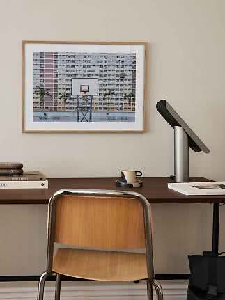 Framed photo print of a basketball hoop in front of apartment blocks above a desk