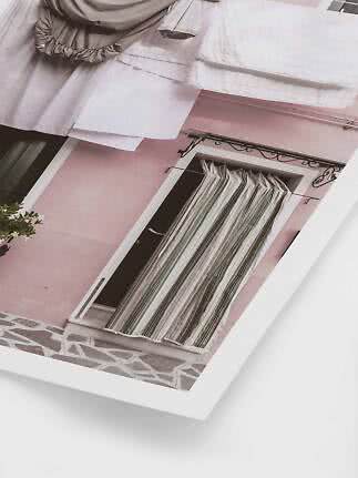 Foto einer rosa Hausfassade mit gestreiftem Türvorhang und heller Wäsche darüber