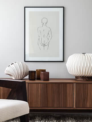Framed minimalist line drawing of a standing woman above a wooden sideboard